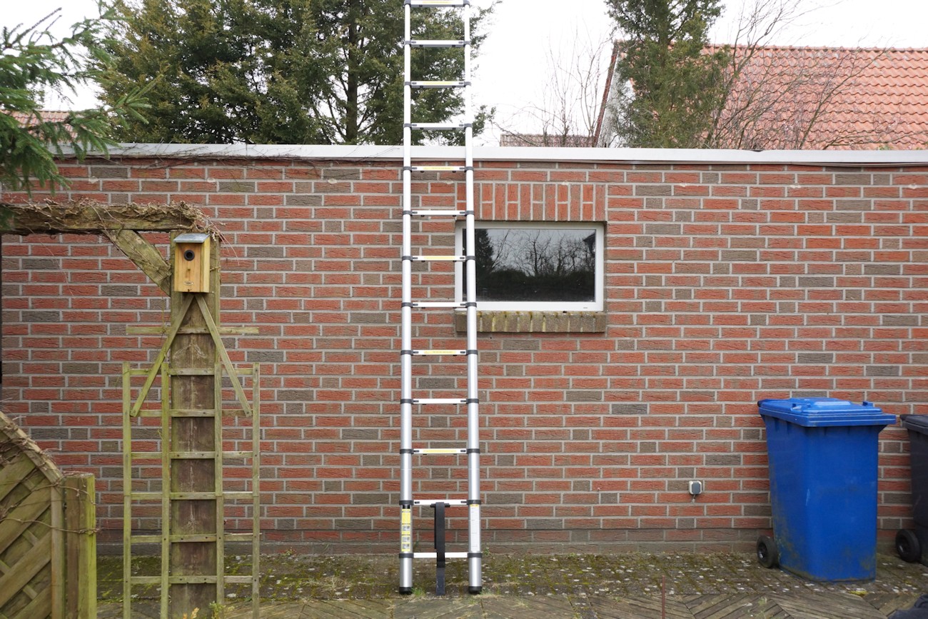 Teleskopleiter im Garten, angelehnt an einer Garage